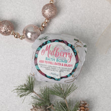 Load image into Gallery viewer, A packaged bath bomb with 'MULBERRY BATH BOMB' label, placed on a surface with pine branches and decorative balls, indicating it is meant to add to a full bath and enjoy the fruit-themed scent and therapeutic benefits.