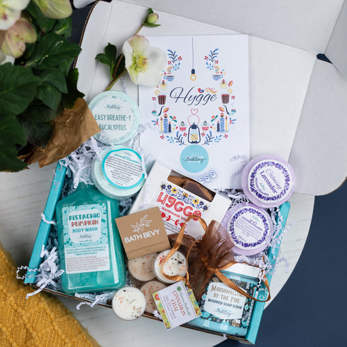 Gifting box with bath bombs, soap, and 'Hygge' themed items on a white surface.