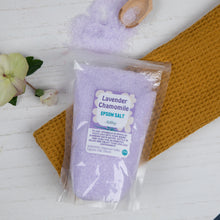 Load image into Gallery viewer, Packaged lavender chamomile Epsom salt on a white surface with a wooden scoop and flowers.
