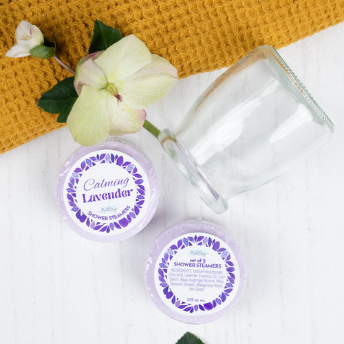 Two glass jars with lavender-themed labels on a white surface with a yellow woven mat.