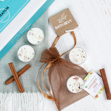 Load image into Gallery viewer, Bath bombs in a brown drawstring bag with cinnamon sticks and a label on a white surface.