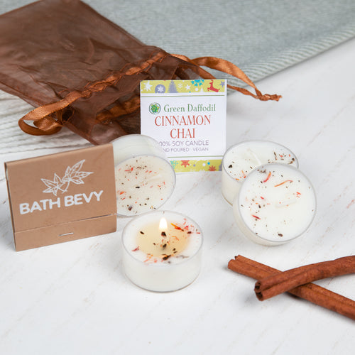 Bath Bevy cinnamon chai candles with packaging and cinnamon sticks on a white surface