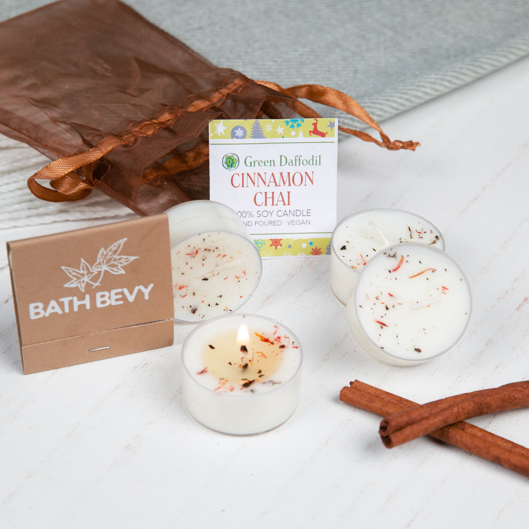 Bath Bevy cinnamon chai candles with packaging and cinnamon sticks on a white surface