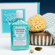 Load image into Gallery viewer, Bottle of pistachio pumpkin body wash with a sponge and towel on a white background