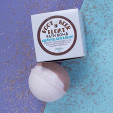 Load image into Gallery viewer, Root Beer Float bath bomb with packaging on a glittery blue and purple background