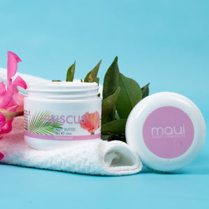 Two jars of Maui Soap Company product with pink flowers and green leaves on a blue background