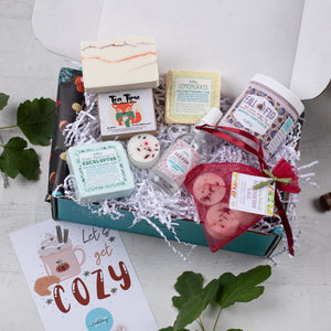 Gift box with bath products and a card on a light background