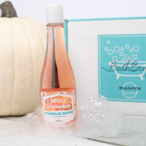 Bottle of 'White Pumpkin' bubble bath with a pumpkin and box in the background