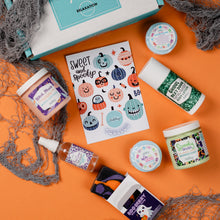 Load image into Gallery viewer, Halloween-themed products including candles, soaps, and a box on an orange background.