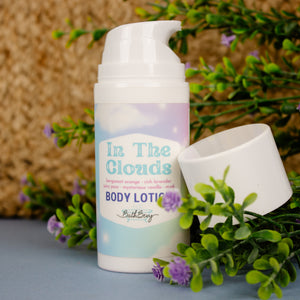Body lotion bottle labeled 'In The Clouds' with greenery and flowers in the background