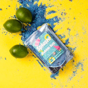 Bath bomb packaging with limes and blue powder on a yellow background