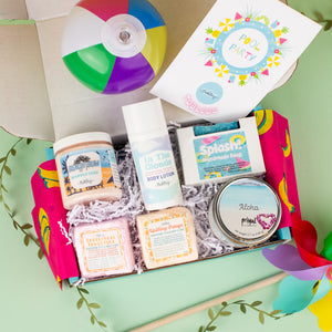 Gift box with beach-themed products including a beach ball on a light green background