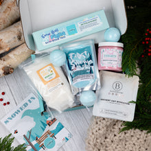 Load image into Gallery viewer, Collection of bath products including bath bombs, soap, and bath salts on a wooden surface with Christmas decorations.