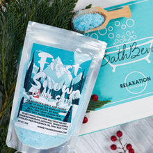 Load image into Gallery viewer, Bath product packaging with 'First Snow' text on a wooden surface with greenery and berries.