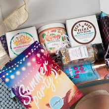 Load image into Gallery viewer, A curated bath and body gift box filled with assorted summer-themed products, including a colorful 'Summer party!' bag, a jar of Melon Mist whipped soap, a Root Beer Float bath bomb, and a bottle of sprinkles, arranged in white packing paper.