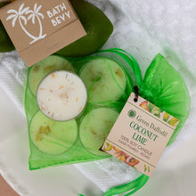 Load image into Gallery viewer, A green mesh bag holding four round green wax candles with one candle removed to show the white wax and botanical flecks. A kraft paper tag reads 'Green Daodhil Coconut Lime' and says '100% Soy Candle'.