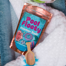 Load image into Gallery viewer, A pouch of Pool Floaty Steamer Dust with a small wooden scoop resting in front of it, placed on white towels with blue water visible in the background.