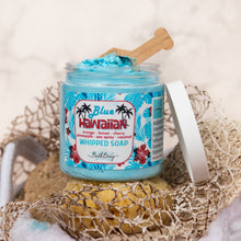 Load image into Gallery viewer, A jar of Bath Bevy Blue Hawaiian Whipped Soap with a wooden scoop, displayed on a spongy beach towel with a sponge and its white lid beside it.