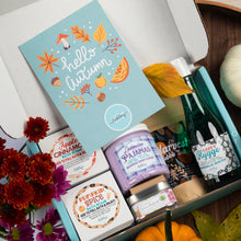 Load image into Gallery viewer, An open gift box filled with fall-themed bath and beauty products, including a light blue 'hello autumn' card, lavender pajamas whipped soap scrub, pumpkin spice bath bomb, and a green bottle of bubble bath, styled with flowers, leaves, and small pumpkins.
