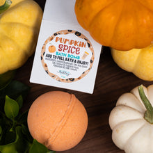 Load image into Gallery viewer, A square white box labeled 'Pumpkin Spice Bath Bomb' sits on a dark wooden surface surrounded by decorative pumpkins and green leaves. An orange bath bomb is placed in front of the box.