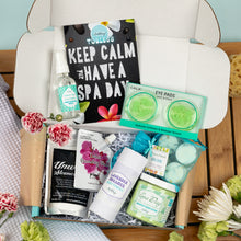 Load image into Gallery viewer, Spa-themed gift box with various items including eye pads and candles on a wooden surface.