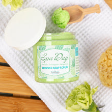 Load image into Gallery viewer, Jar of 'Spa Day' whipped soap scrub with a wooden spoon and green flowers on a white towel.