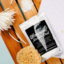 Load image into Gallery viewer, Package of 'Unwind Steamer Dust' on a wooden surface with a sponge and flowers.