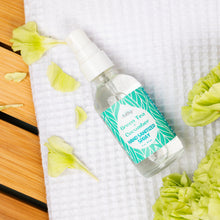 Load image into Gallery viewer, Hand sanitizer spray bottle with green tea and cucumber label on a white towel with flowers