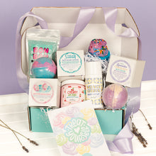 Load image into Gallery viewer, Gifting box with bath bombs, body lotion, and other self-care items on a white surface with a purple background.