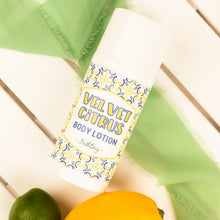 Load image into Gallery viewer, Body lotion bottle labeled 'Velvet Citrus' with a decorative label on a wooden surface.