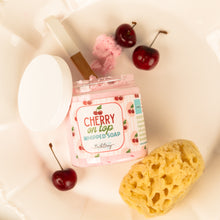 Load image into Gallery viewer, Pink whipped soap bar with cherry design labeled 'Cherry on Top' next to cherries and a yellow sponge on a white background.