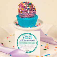 Load image into Gallery viewer, Bath bomb cupcake with colorful sprinkles on a white stand, accompanied by a label.
