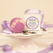 Load image into Gallery viewer, Lavender Champagne bath bomb with packaging on a white stand with purple ribbons.