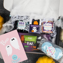 Load image into Gallery viewer, A Halloween-themed gift box filled with bath and beauty treats, including scented soap bars, a pink tubless sheet with ghost graphics, and blueshower steamers, surrounded by fake cobwebs and small pumpkins.