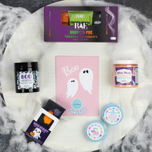 Load image into Gallery viewer, A Halloween-themed bath and body gift set arranged on a white marble tray with faux cobwebs. The set includes a purple box of RAE Haunted Fog Shower Steamers, a pink Boo Tubless card, a black jar of Boo Whipped Soap, a peach-colored Witch, Pease Whipped Soap Scrub, and several small round and square containers with colorful labels.