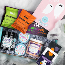 Load image into Gallery viewer, A Halloween-themed gift box arrangement from RAE , featuring shower steamers in green, orange, and black, whipped soap, bath salts, a pink ghost card, with faux cobwebs on a white background.