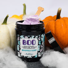 Load image into Gallery viewer, A jar of Bath Bevy 'BOO' Whipped Soap sits on a dark surface surrounded by faux cobwebs, white and orange pumpkins, and a wooden spoon with lavender whipped soap visible at the top.