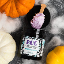 Load image into Gallery viewer, A Halloween-themed whipped soap product in a black jar with a purple whipped soap scoop resting on top. The jar is surrounded by decorative pumpkins, white faux cobwebs, and a dark gray textured background.