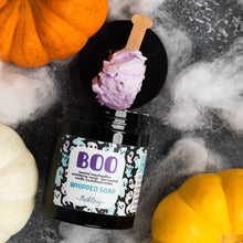 Load image into Gallery viewer, A Halloween-themed whipped soap in a black jar with a purple whipped soap scoop resting on top. The jar is surrounded by decorative pumpkins, white faux cobwebs, and a dark gray textured background.