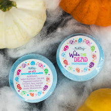 Load image into Gallery viewer, Two round Bath Bevy shower steamers in light blue packaging with colorful skull-patterned labels, styled on a white textured surface with decorative pumpkins around them.