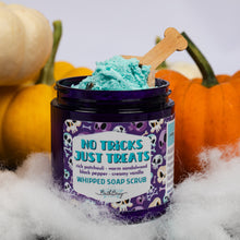 Load image into Gallery viewer, A jar of whipped soap scrub by Bath Bevy sits on white faux fur with a bone-shaped wooden spoon, surrounded by pumpkins and fake cobwebs. The label reads 'NO TRICKS JUST TREATS'.