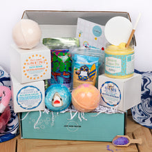 Load image into Gallery viewer, Bath product set with bath bombs, soaps, and other items in a box on a wooden surface.
