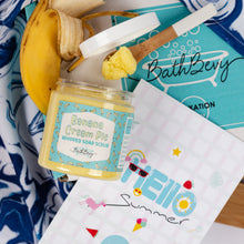 Load image into Gallery viewer, Jar of Banana Cream Pie scented soap scrub with a brush on a blue and white patterned towel.