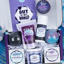 Load image into Gallery viewer, An open gift box filled with bath and body items: a purple soap bar, a bag of Star Dust fizzy dust, Twilight Woods body lotion, a round bath bomb, a marbled bath bomb, and two boxed soaps labeled Aurora Borealis and Galaxy. A purple card behind the items reads 'OUT of this WORLD'.
