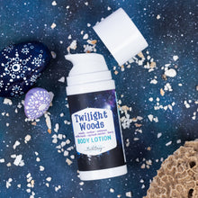 Load image into Gallery viewer, Twilight Woods Body Lotion pump bottle with its cap off, styled on a dark blue speckled background with decorative stones and textured elements. The label reads 'Twilight Woods' and 'BODY LOTION'.