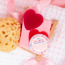 Load image into Gallery viewer, Handmade soap with heart design and a yellow sponge on pink petals